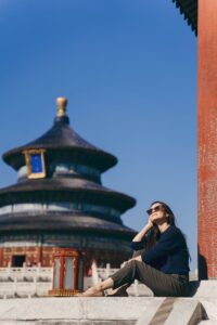 Una viajera sonriente contemplando el Templo del Cielo en Beijing bajo un cielo azul despejado; una experiencia cultural única incluida en nuestros viajes personalizados a China.